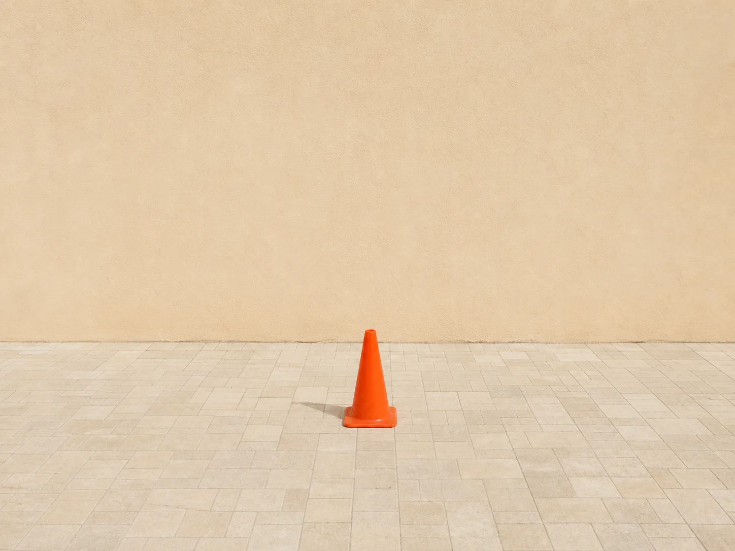 Recommended orange cone surrounded by consistent pale wall and repeating stone paving